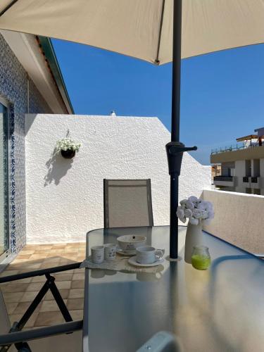 a glass table on a balcony with an umbrella at Barra Azul - Beach Apartment in Praia da Barra