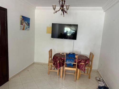 a dining room with a table and a tv on a wall at Forest near to the beach امام المستشفى الجامعي طنجة in Daidatz