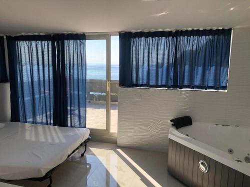 Un dormitorio con una cama y una bañera y una ventana. en Taormina loview, en Giardini Naxos
