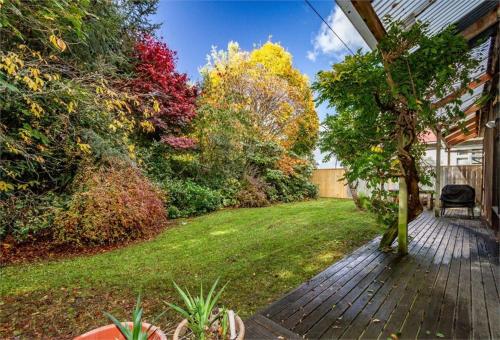 a backyard with a wooden walkway and trees at The Shed in Rangataua