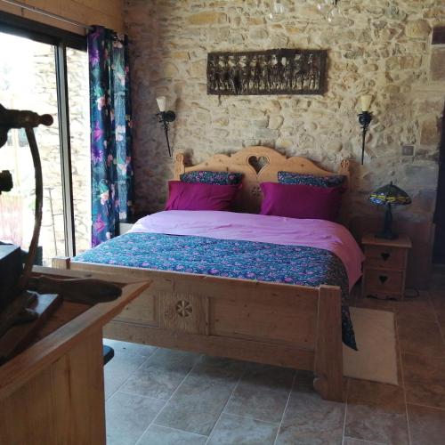 - une chambre avec un lit en bois et des oreillers roses dans l'établissement La bergerie d'antan, à Castelreng