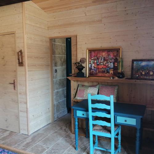 une cabine en bois avec une table bleue et une chaise dans l'établissement La bergerie d'antan, à Castelreng