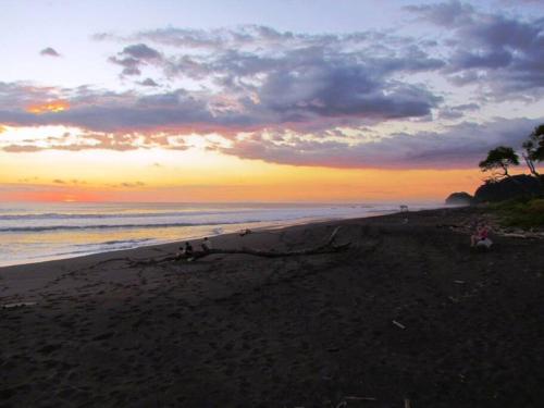 a beach with people sitting on the sand at sunset at #17A Hermosa Beach Bungalow 1st floor 1 bedroom Apt in Playa Hermosa
