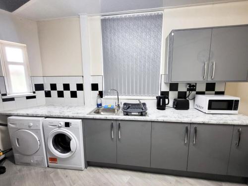 a kitchen with a washing machine and a microwave at Stay Sleep Rest - Oldham in Oldham