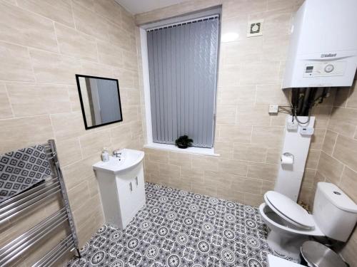 a bathroom with a toilet and a sink and a window at Stay Sleep Rest - Oldham in Oldham