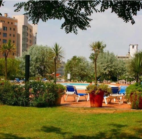 a park with chairs and a pool with palm trees at BestHomeStay- Lisbon- Garden, Pool & Garage in Lisbon