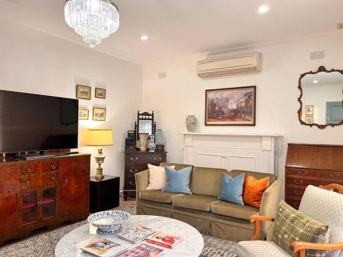 a living room with a couch and a tv at Sunny Retro Home Burnside area in Rose Park
