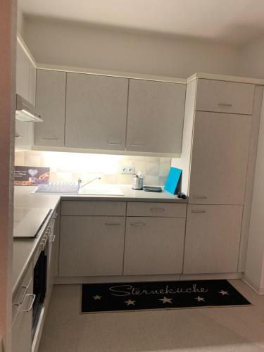 a kitchen with white cabinets and a kitchen rug on the floor at Wunderschöne 2 Zimmer Wohnung in Wiedenbrück -7- in Rheda-Wiedenbrück