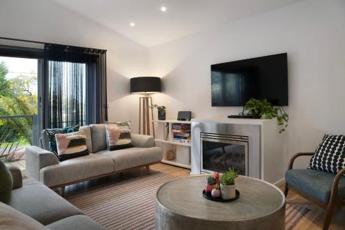 a living room with a fireplace and a tv at Delfryn - stylish and modern, with great views in Daylesford