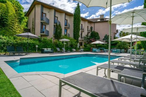 a swimming pool with chairs and umbrellas next to a building at Best Western Bridge Hotel Lyon East in Jons
