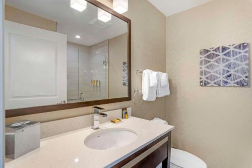 a bathroom with a sink and a toilet and a mirror at Best Western Plus Philadelphia-Pennsauken Hotel in Cherry Hill