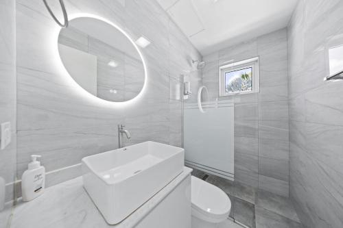 a white bathroom with a sink and a mirror at Apricity Suites Aruba in Noord