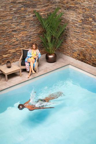 a woman sitting in a chair next to a swimming pool at art'otel amsterdam in Amsterdam