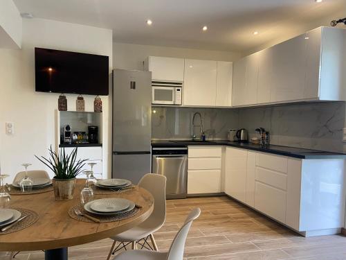 une cuisine avec une table en bois et des armoires blanches dans l'établissement Villa vue mer luxury à 5 minutes à pied du centre ville de Porto Vecchio, à Porto-Vecchio