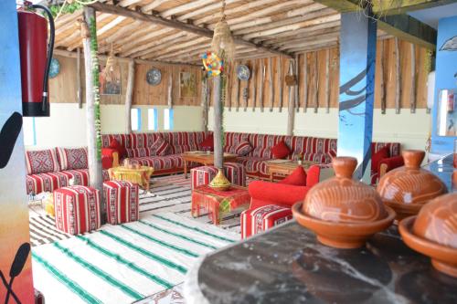 a room with red chairs and tables and vases at Azour House in Taghazout