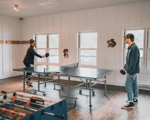 two men playing ping pong in a room with a ping pong table at Lakefront & Mountain View - 1 Bedroom Resort Suite in Lac-Superieur