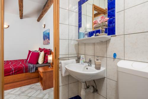 a small bathroom with a sink and a bed at Studio Punat 15451a in Punat
