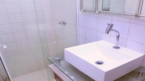 a bathroom with a white sink and a shower at Pertinho da Praia Copacabana 4 pessoas in Rio de Janeiro