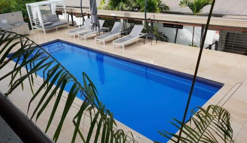 a large blue swimming pool with lounge chairs around it at Monsoon Luxury Apartment in Port Douglas
