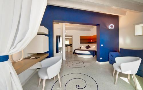 a bedroom with blue walls and a bed with white chairs at Zafran Boutique Hotel in Donnalucata