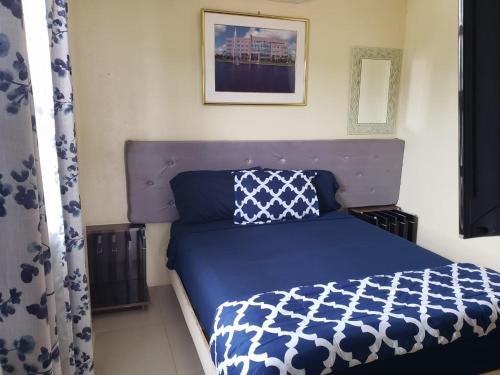 Schlafzimmer mit einem Bett mit einer blauen und weißen Bettdecke in der Unterkunft DB Tower Vacation Rental in Belize City