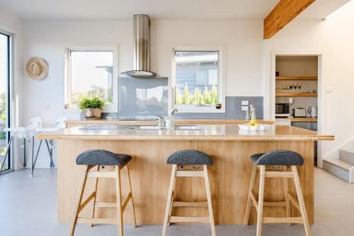 a kitchen with a wooden island with two bar stools at Haven Views Harmers Haven in Cape Paterson