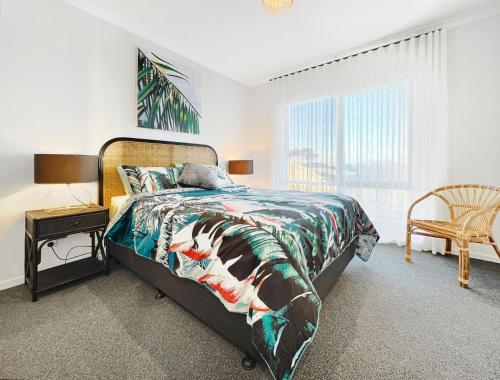 a bedroom with a bed and a chair and a window at Shelley Beach Retreat Kilcunda in Kilcunda
