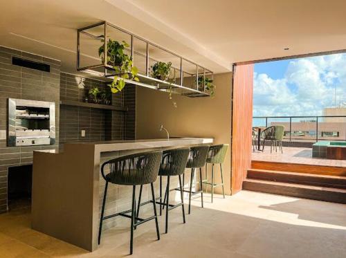 a kitchen with a bar with chairs and a balcony at Praia do Cabo Branco- FLAT DO BZ- 2 quartos in Tambaú