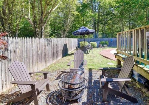 a backyard with two chairs and a grill and an umbrella at 3 BR 2 BA Modern home with private hot tub, fire pit and lake view, Dogs ok! in Tobyhanna