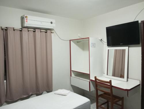 a room with a desk and a television and a chair at Hotel Lisboa II in São José dos Campos