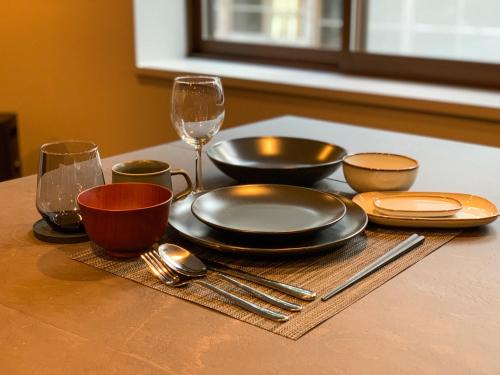 a table with plates and bowls and wine glasses at 佐渡古民家ステイ さどまり 大和の家 in Sado