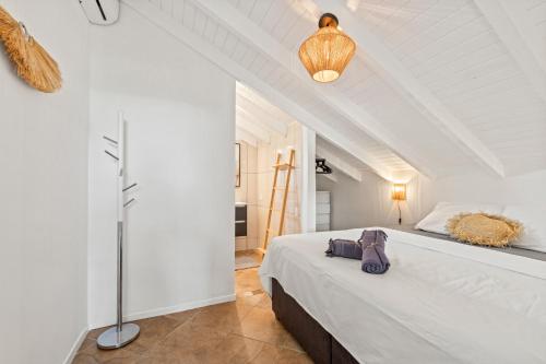 a white bedroom with a bed and a lamp at Cocoloft Curacao in Jan Thiel