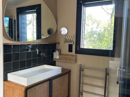 une salle de bain avec un lavabo et un miroir dans l'établissement Maison dans les arbres, proche plage, cheminée, jardin, parking - FR-1-652-46, à Saint-Jean-de-Monts