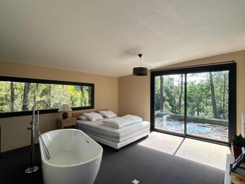 une salle de bain avec une baignoire, un lit et une fenêtre dans l'établissement Maison dans les arbres, proche plage, cheminée, jardin, parking - FR-1-652-46, à Saint-Jean-de-Monts