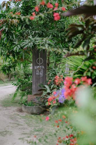 a sign in the middle of a garden with flowers at Boonya Swiss Home in Chaloklum
