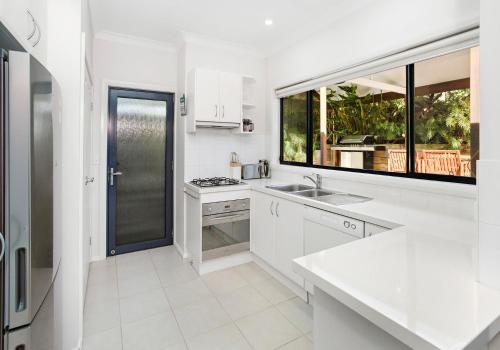 a white kitchen with a sink and a window at Werri Beach Hideaway in Gerringong