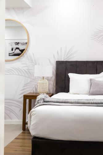 a bedroom with a bed with a mirror and a table at Hastings Suites by Stay Noosa in Noosa Heads