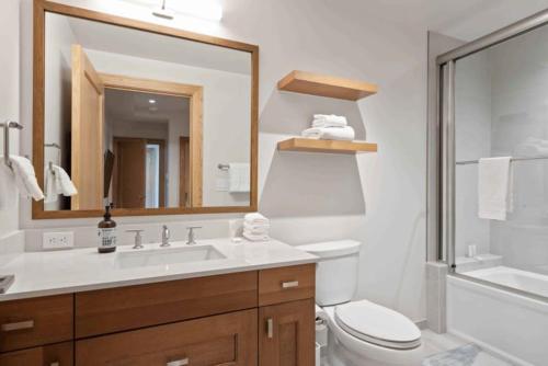 a bathroom with a sink and a toilet and a mirror at Riverfront Lodge 403 by East West Hospitality in Beaver Creek