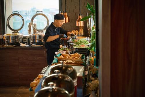 a chef preparing food at a buffet in a restaurant at CLASSYC Hotel in Hanoi