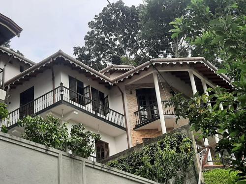 a white house with balconies and trees at Laaya Kandy in Kandy