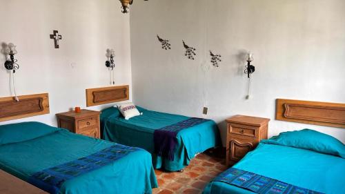 Zimmer mit 3 Betten und einem Kreuz an der Wand in der Unterkunft Hacienda de Pueblito Atotonilco in Banda