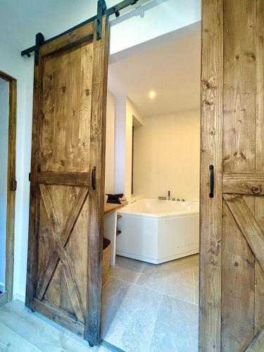 La salle de bains est pourvue d'une porte en bois et d'une baignoire. dans l'établissement cinéma & balnéo privatifs, à Montfrin