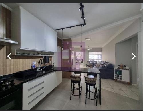 a kitchen with white cabinets and a black counter top at Apartamento Praia das Pitangueiras - Condomínio Golden Tower in Guarujá