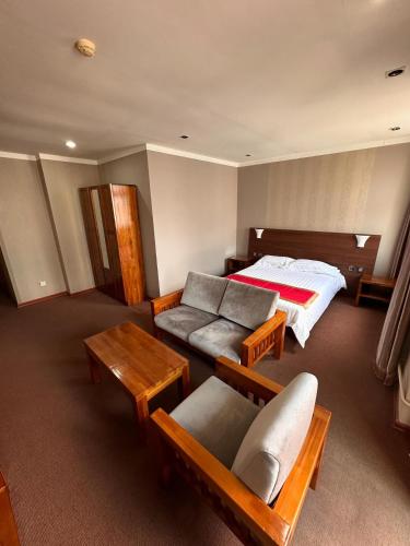 ウランバートルにあるZuut hotelのベッドルーム(ベッド1台、ソファ、テーブル付)