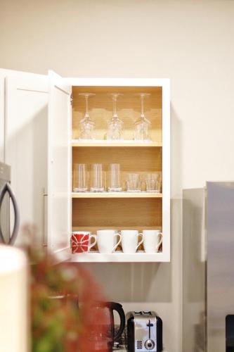 a white cabinet with cups and glasses in it at RiverWinds - Modern Charm Near Shenandoah National Park in Luray