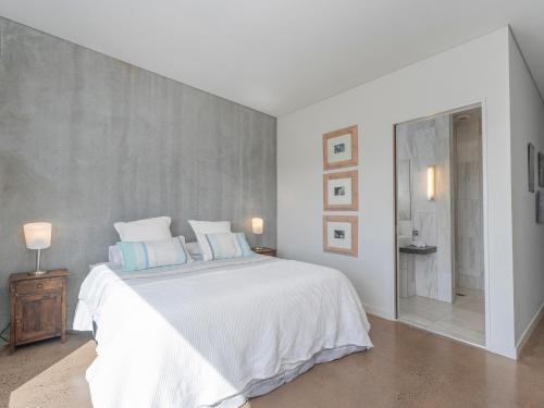 a white bedroom with a large bed with blue pillows at Te Punga Lodge - Whangapoua Beach Luxury Villa in Whangapoua