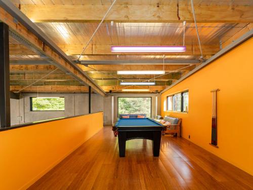 a pool table in a room with an orange wall at Te Punga Lodge - Whangapoua Beach Luxury Villa in Whangapoua