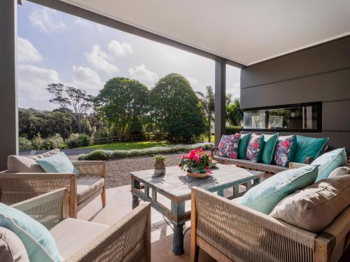 a patio with couches and a table with flowers on it at Te Punga Lodge - Whangapoua Beach Luxury Villa in Whangapoua