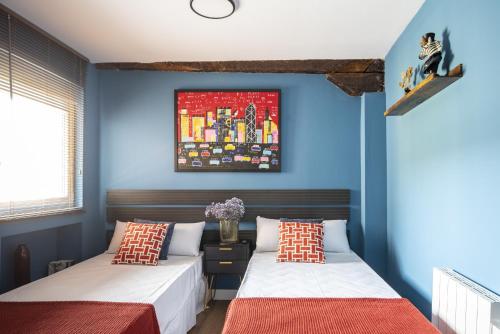 two beds in a room with blue walls at Loft Garmendia con PlayStation in Santander