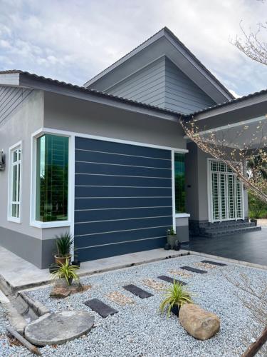 a house with a blue garage door at Majestic Homestay - Pasir Puteh in Pasir Puteh